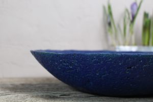 Dekoschale blau mit Blumendeko im Hintergrund