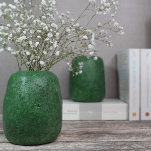 mittelgroße, grüne Vase aus Altpapier mit Schleierkraut dekoriert und Bücher im Hintergrun