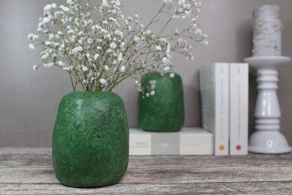 mittelgroße, grüne Vase aus Altpapier mit Schleierkraut dekoriert und Bücher im Hintergrun